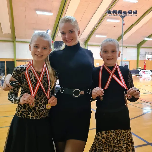 To dansere med medaljer sammen med instruktøren
